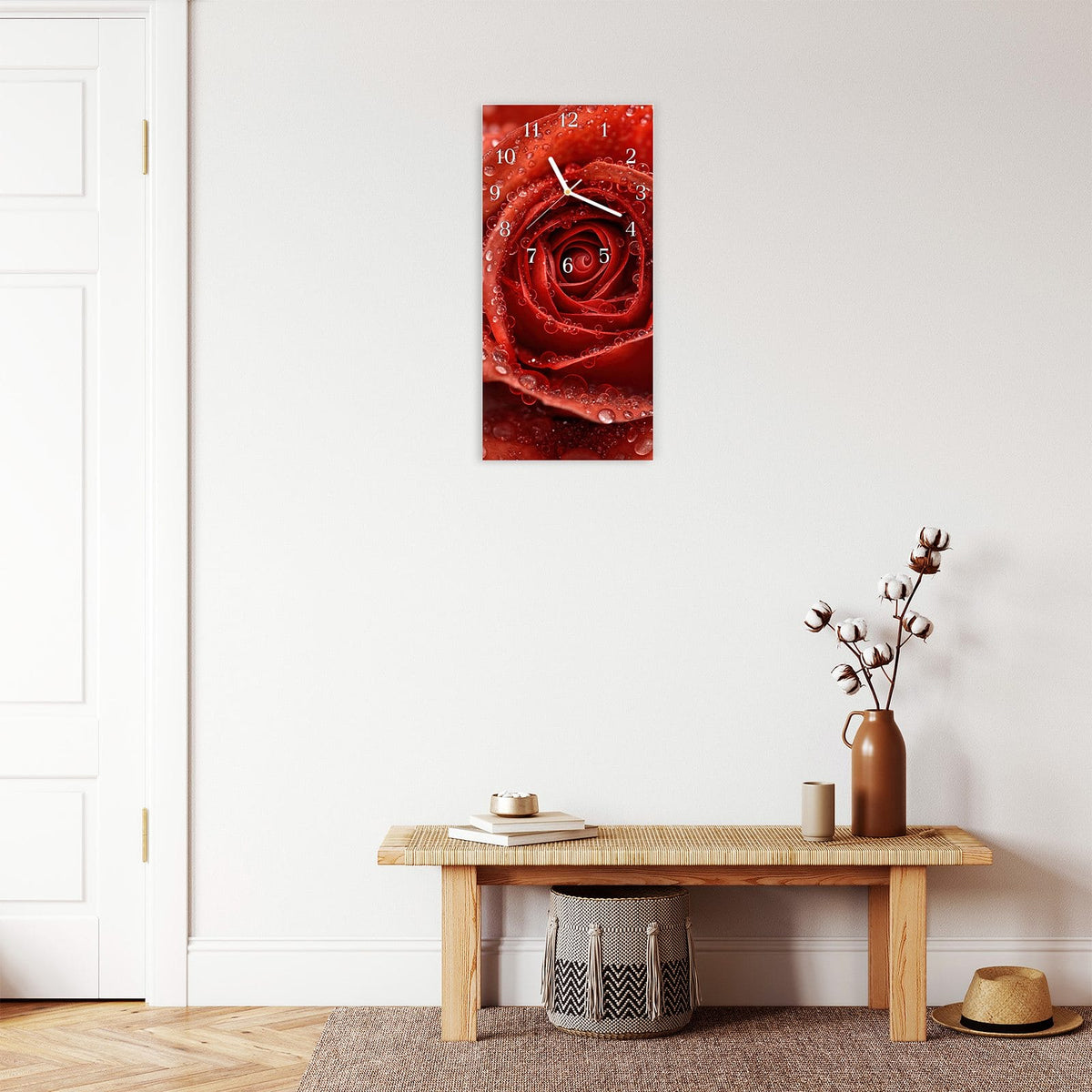 Wanduhr aus Glas im Hochformat Rote Rose mit Tropfen mit Ziffernblatt Klassisch über einer Holzbank im Flur