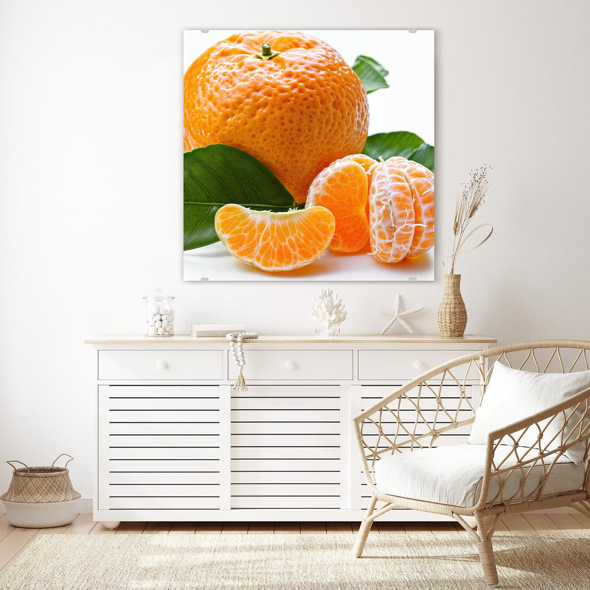 Glasbild Frische Mandarine an der Wand – Ganze Mandarine mit grünen Blättern, davor geschälte Frucht und einzelne Spalten vor Weiß