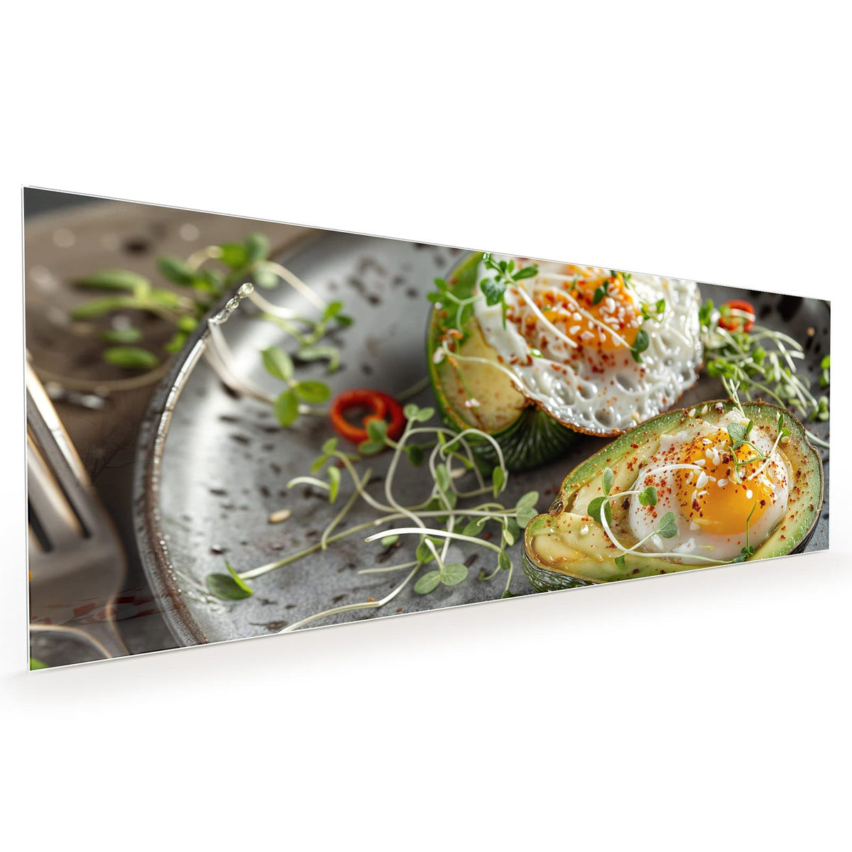 Küchenrückwand aus Glas im Hochformat: Zwei Avocadohälften mit darin gegartem Ei, Kresse, Chiliflocken und Sesam auf dunklem Teller. #grösse_40 x 100 cm #grösse_50 x 125 cm #grösse_60 x 150 cm