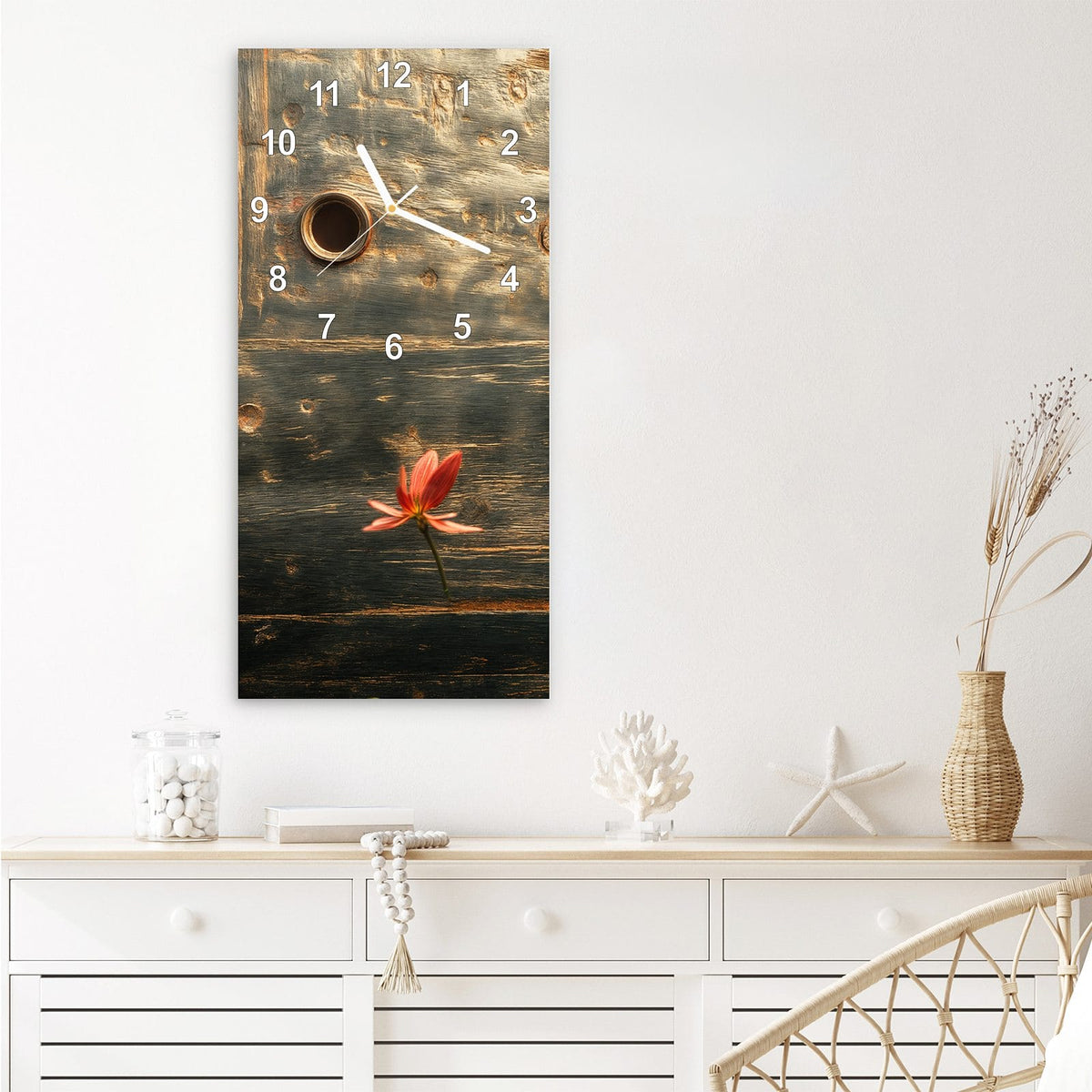 Wanduhr aus Glas im Hochformat Rote Blüten am Metall mit Ziffernblatt Modern über einem weißen Sideboard