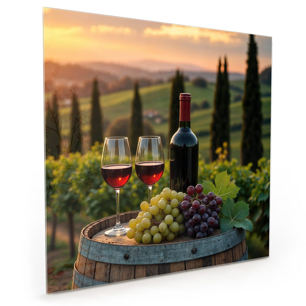 Küchenrückwand aus Glas im quadratischen Format mit Motiv Rotwein im Weinberg: Rotweinflasche, zwei gefüllte Gläser und Trauben auf einem Fass vor Rebhügeln #grösse_40 x 40 cm #grösse_50 x 50 cm #grösse_60 x 60 cm