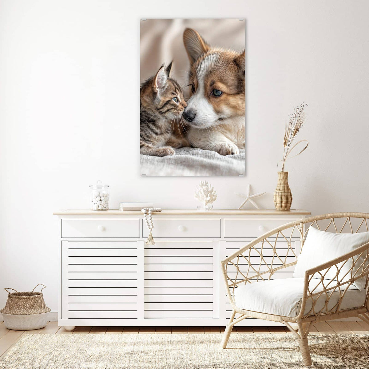 Wandbild aus Glas Welpe und Kätzchen über einem weißen Sideboard neben einem Rattansessel