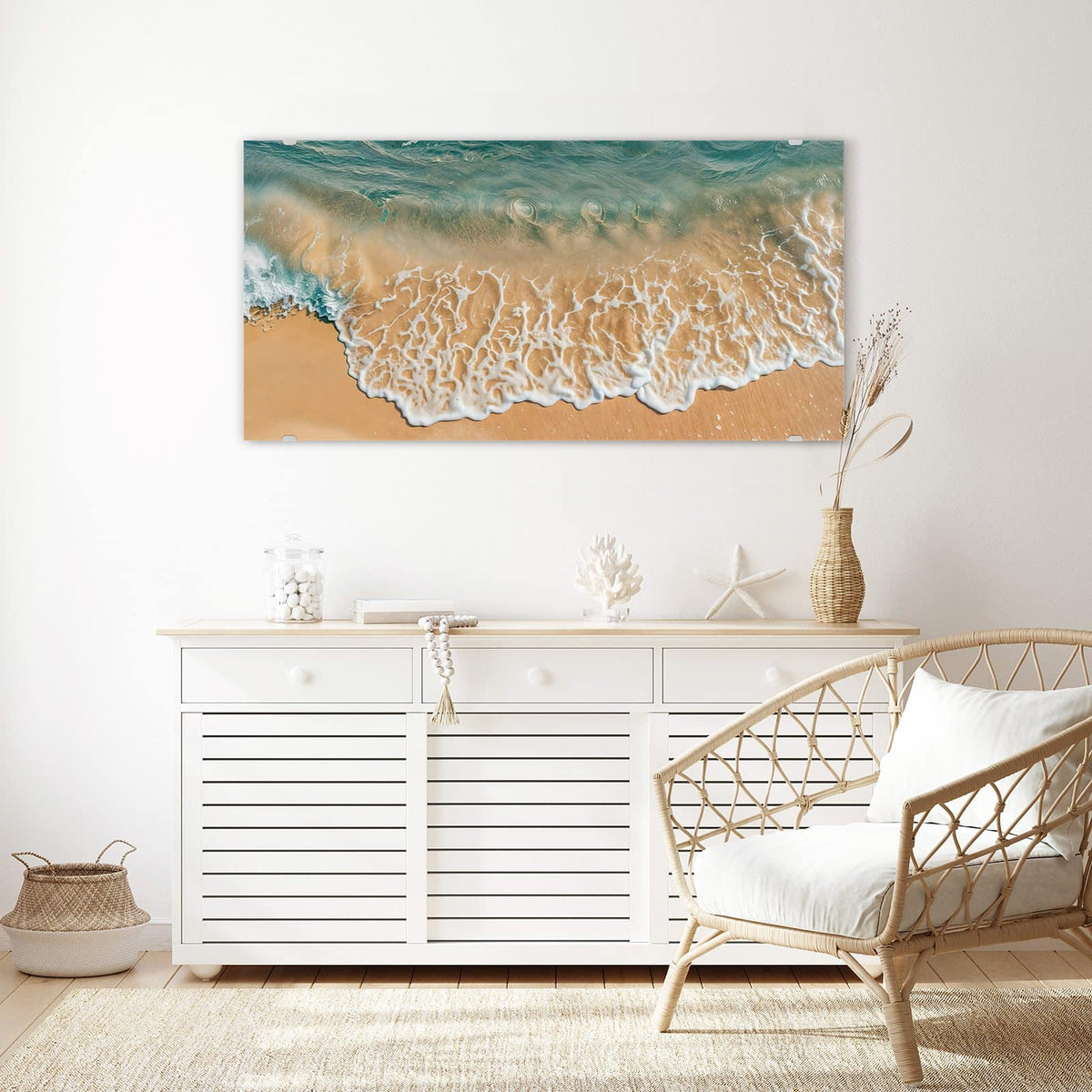 Wandbild aus Glas Meeresschaum auf Sand über einem weißen Sideboard neben einem Rattansessel
