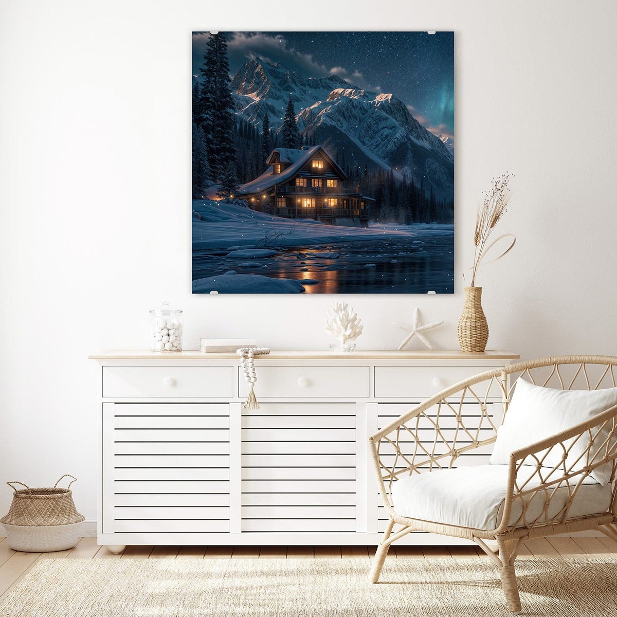 Glasbild Berghütte im Winter an der Wand – Erleuchtetes Holzhaus im Schnee vor Bergkette und Sternenhimmel