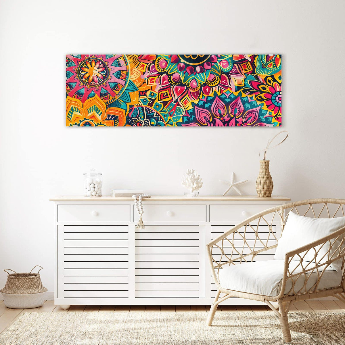 Wandbild aus Glas Bunte Mandalas über einem weißen Sideboard neben einem Rattansessel