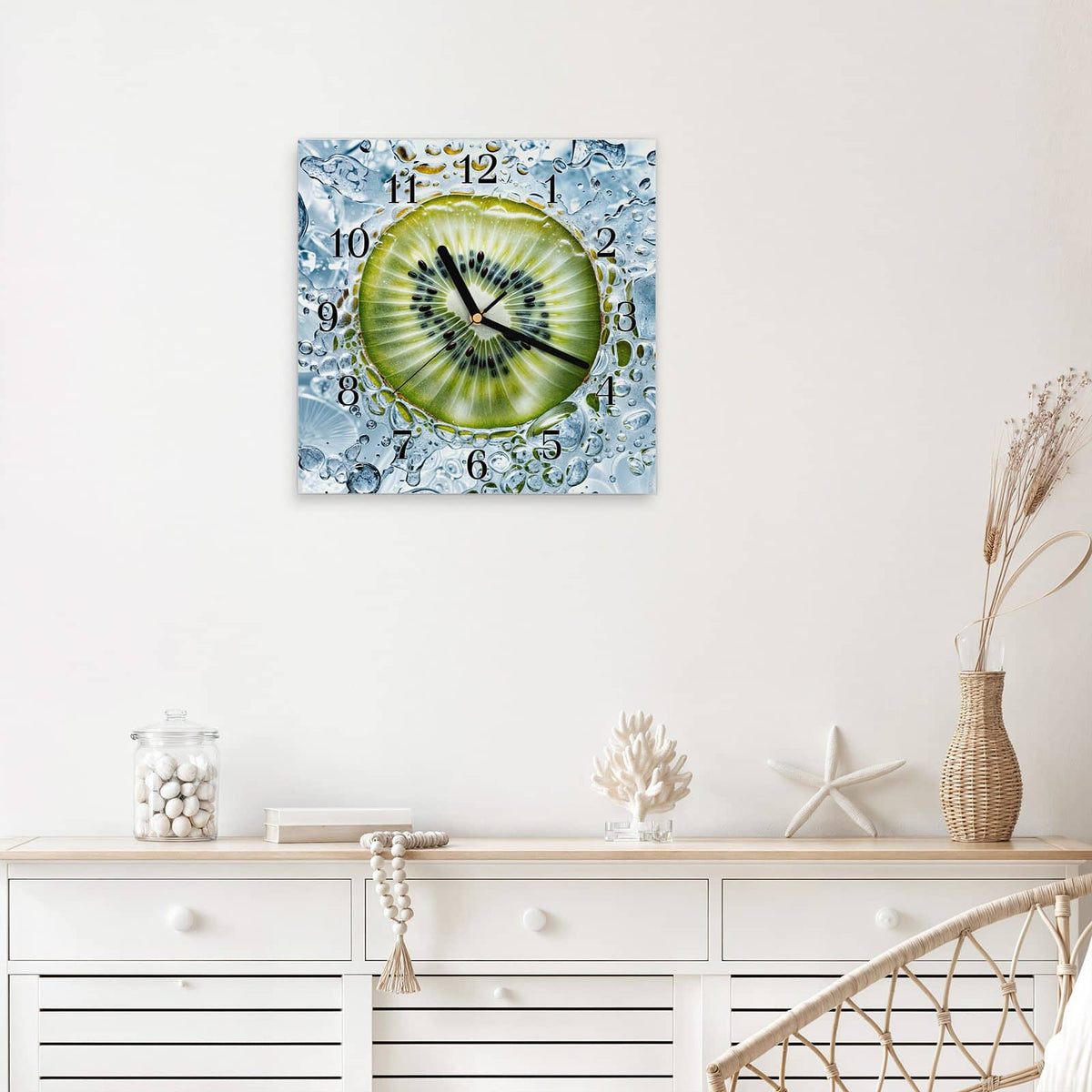 Quadratische Wanduhr aus Glas Kiwi in Wasserblasen mit Ziffernblatt Klassisch über einem weißen Sideboard