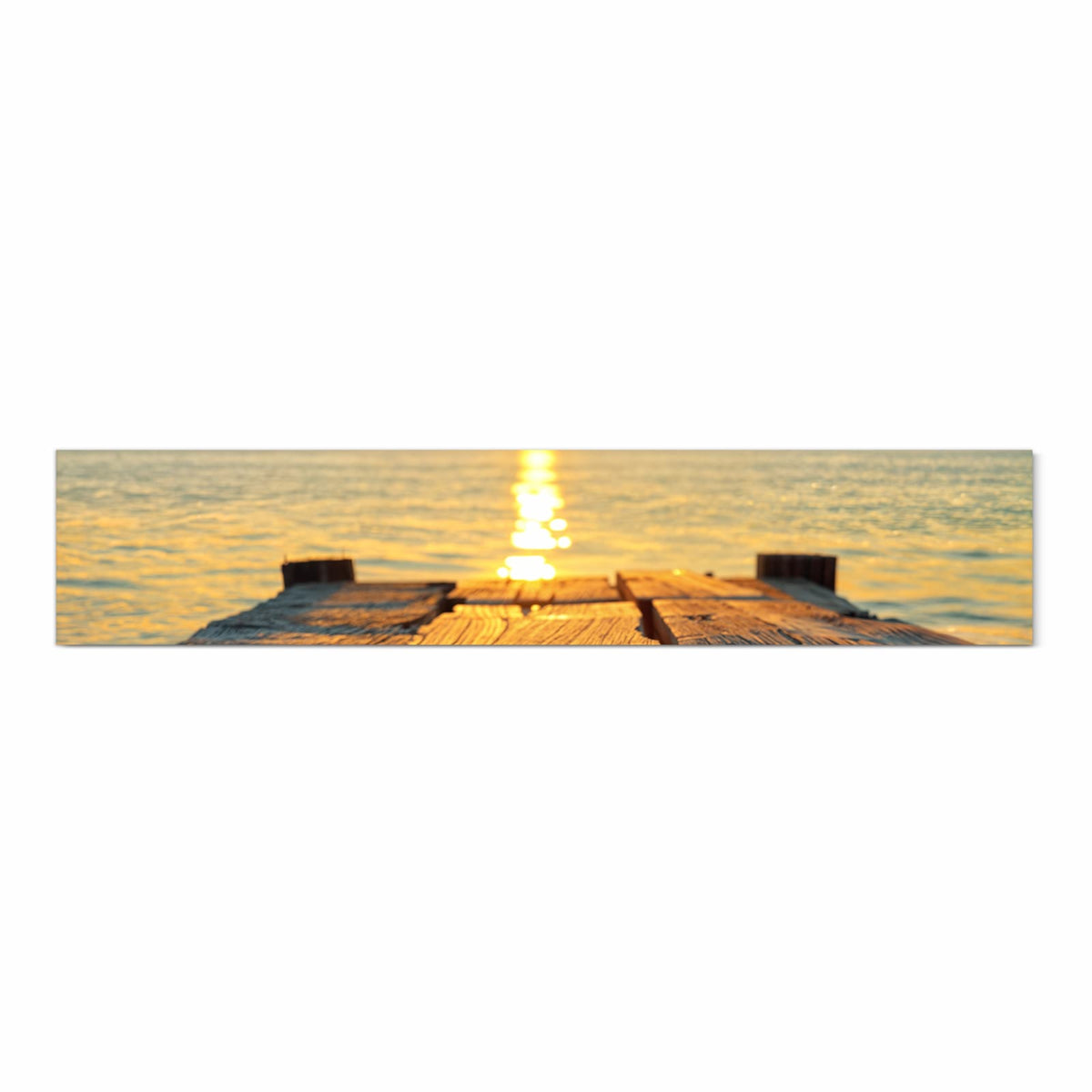 Verwitterte Holzplanken eines Stegs, dahinter Sonnenuntergang über dem Meer