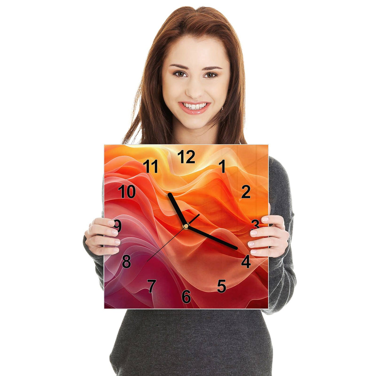 Quadratische Wanduhr aus Glas Orange Seidenfalten in zwei Händen gehalten – Größenvergleich, 30 × 30 cm