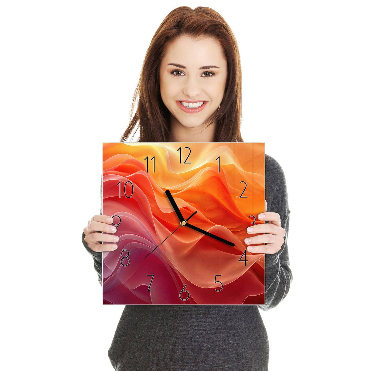 Quadratische Wanduhr aus Glas Orange Seidenfalten in zwei Händen gehalten – Größenvergleich, 30 × 30 cm