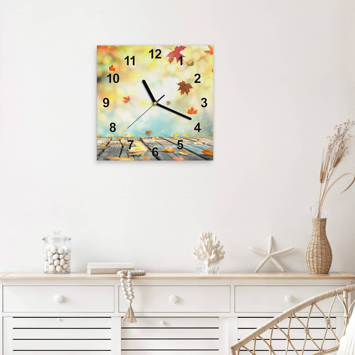 Quadratische Wanduhr aus Glas Herbstlaub auf Holz mit Ziffernblatt Modern über einem weißen Sideboard