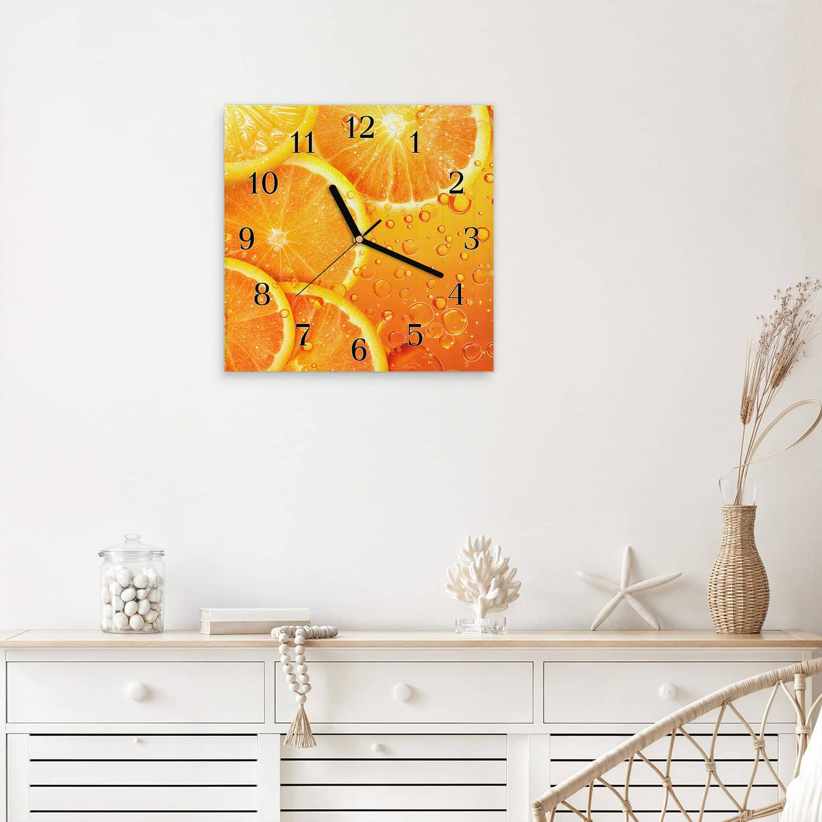 Quadratische Wanduhr aus Glas Sprudelnde Orangen mit Ziffernblatt Klassisch über einem weißen Sideboard