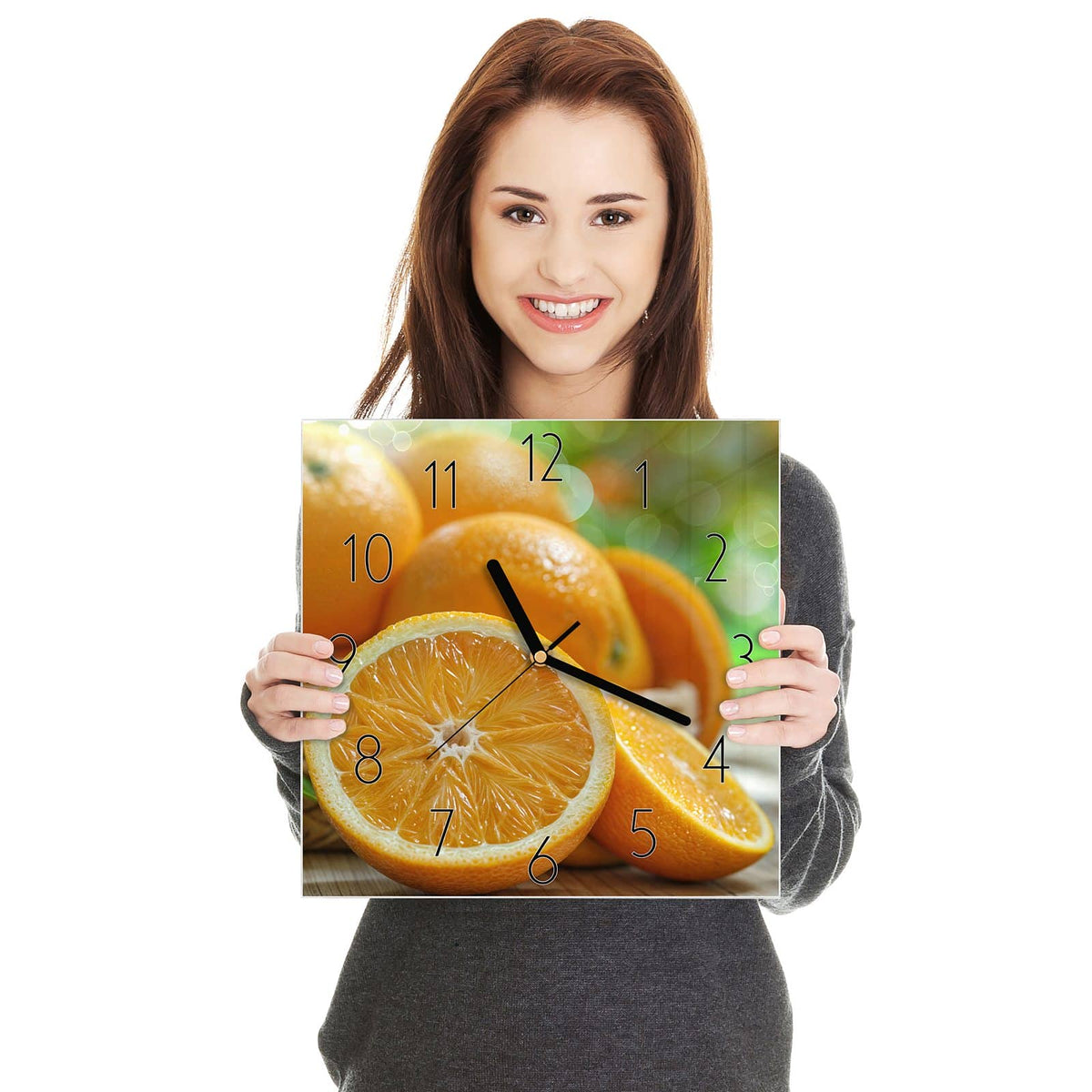 Quadratische Wanduhr aus Glas Orangen auf Holz in zwei Händen gehalten – Größenvergleich, 30 × 30 cm