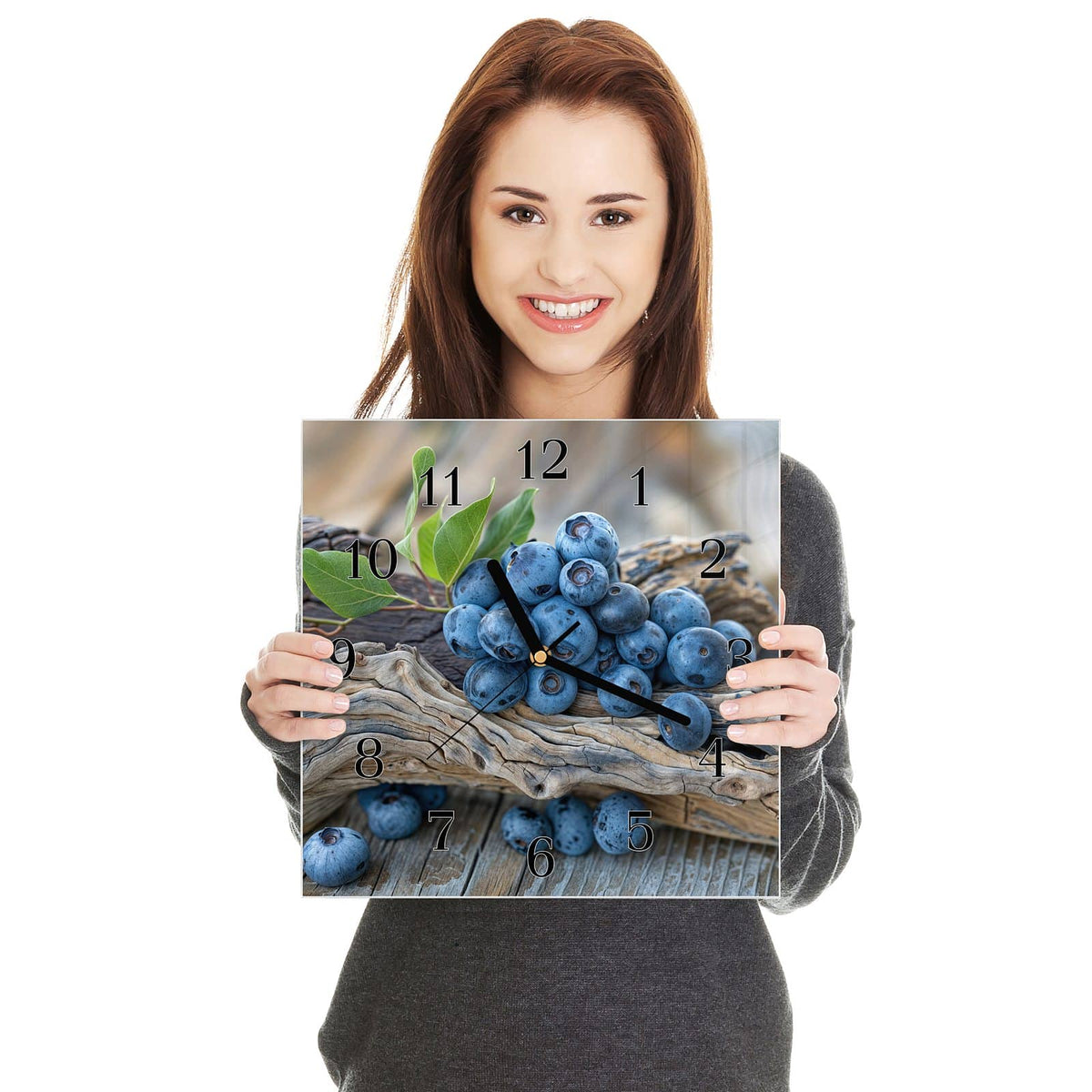 Quadratische Wanduhr aus Glas Treibholz und Blaubeeren in zwei Händen gehalten – Größenvergleich, 30 × 30 cm