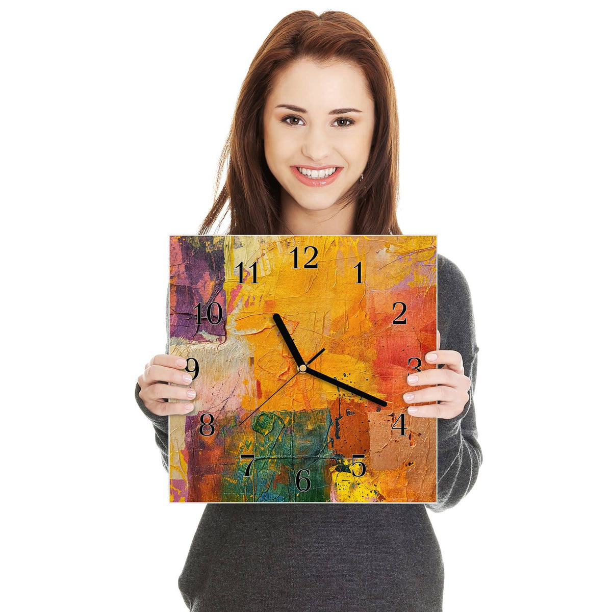 Quadratische Wanduhr aus Glas Farbflächen in Gelb in zwei Händen gehalten – Größenvergleich, 30 × 30 cm