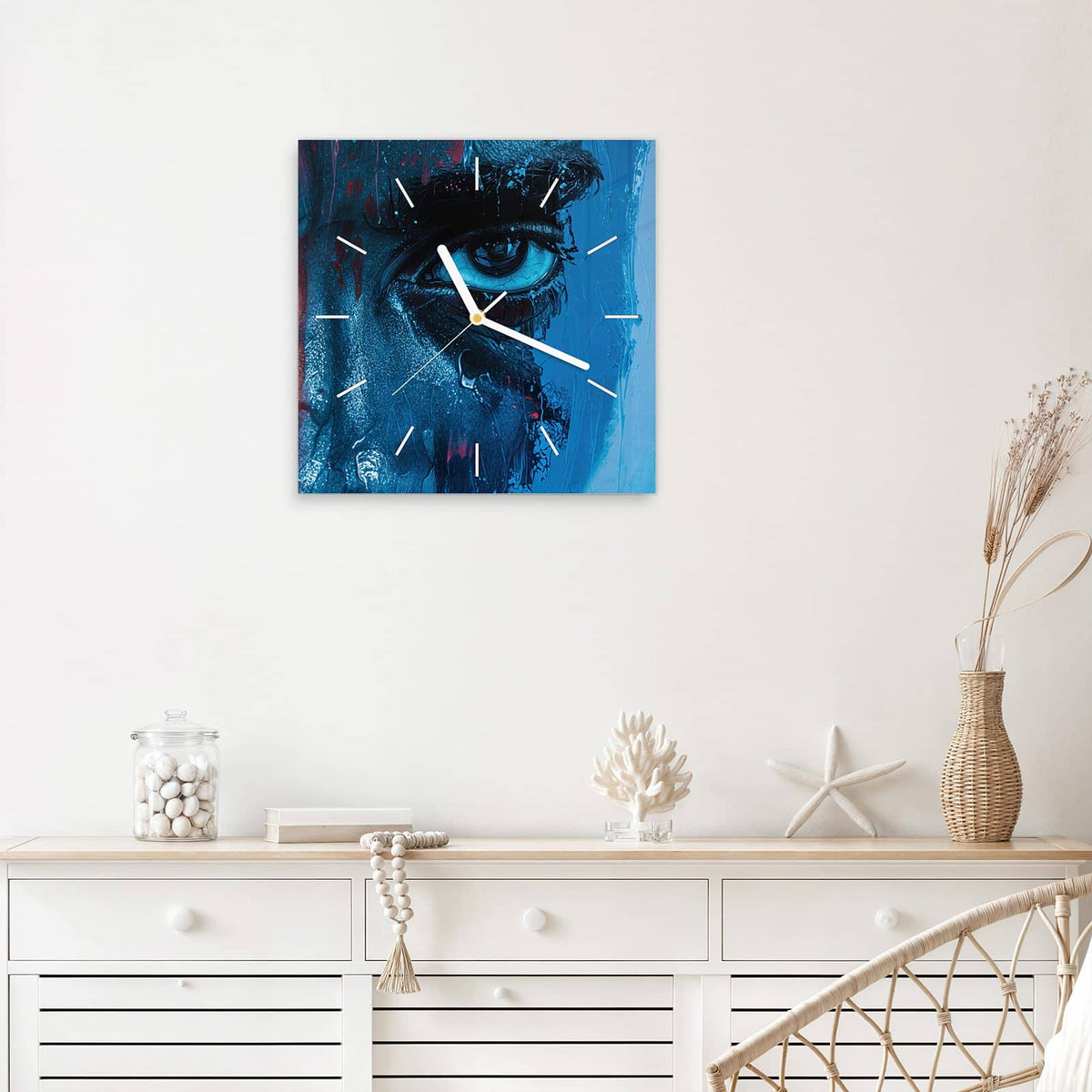 Quadratische Wanduhr aus Glas Gemaltes Auge in Blau mit Ziffernblatt Linie über einem weißen Sideboard