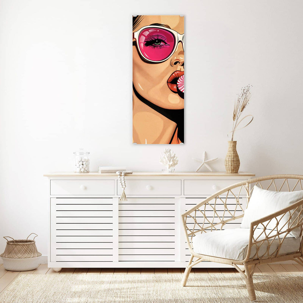 Wandbild aus Glas Pinke Sonnenbrille über einem weißen Sideboard neben einem Rattansessel