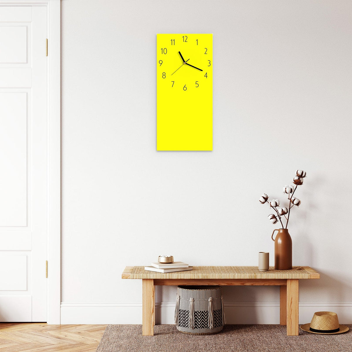 Wanduhr aus Glas im Hochformat Zitronengelb mit Ziffernblatt Elegant über einer Holzbank im Flur