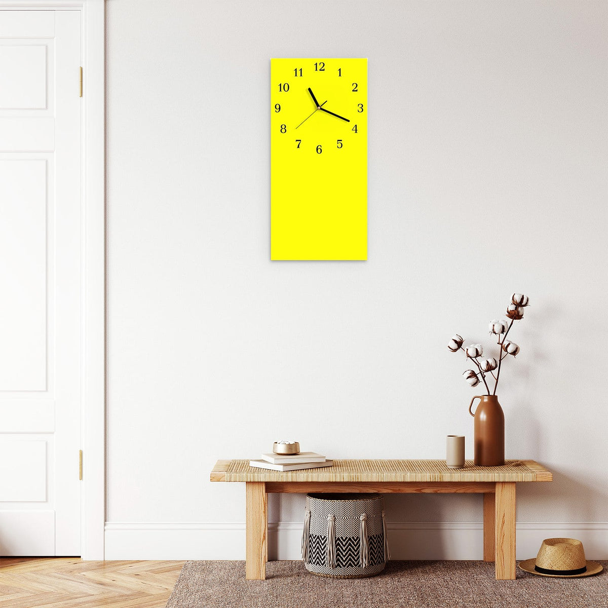 Wanduhr aus Glas im Hochformat Zitronengelb mit Ziffernblatt Klassisch über einer Holzbank im Flur