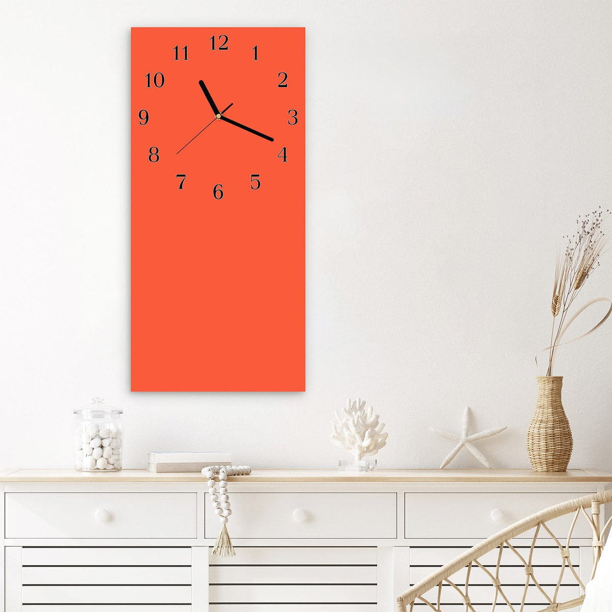 Wanduhr aus Glas im Hochformat Rotoranger Hintergrund mit Ziffernblatt Klassisch über einem weißen Sideboard