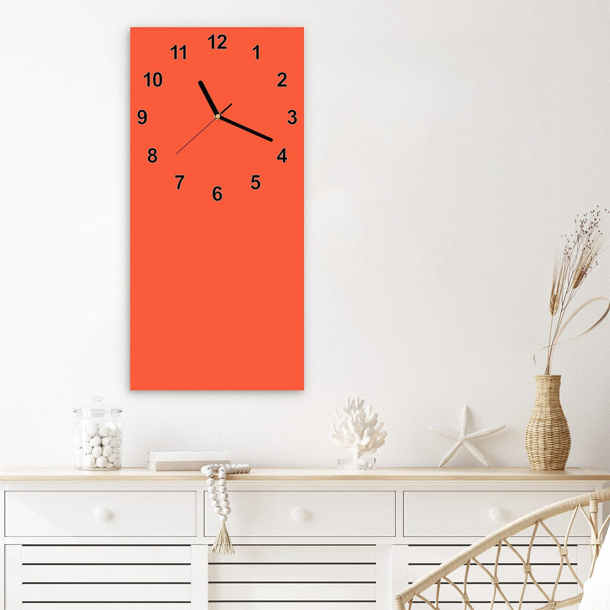 Wanduhr aus Glas im Hochformat Rotoranger Hintergrund mit Ziffernblatt Modern über einem weißen Sideboard