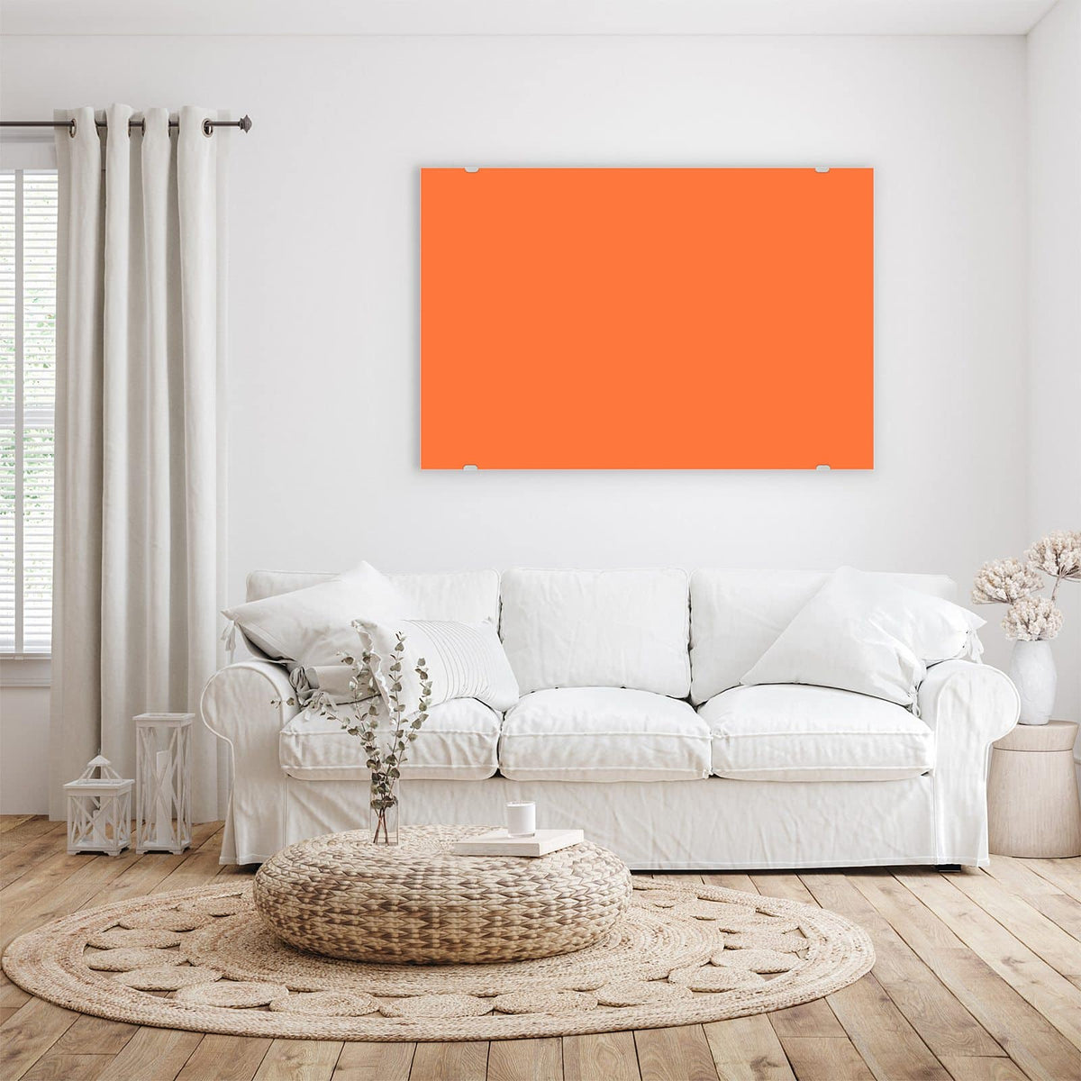 Wandbild aus Glas Korallenorange über einem weißen Sofa im hellen Wohnzimmer