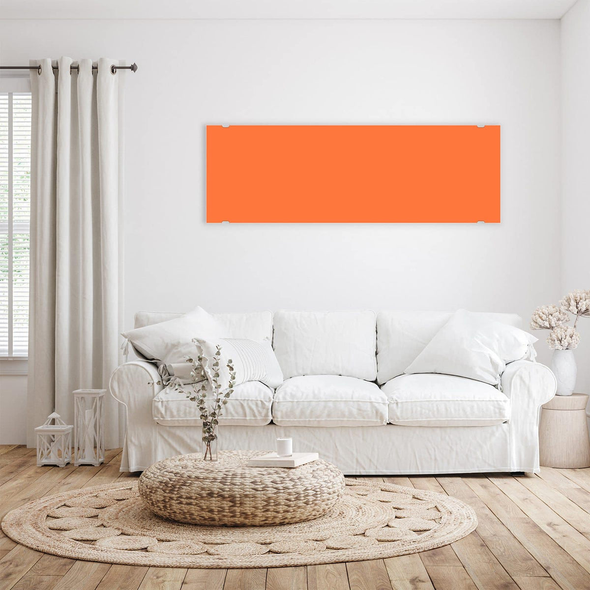 Wandbild aus Glas Korallenorange über einem weißen Sofa im hellen Wohnzimmer
