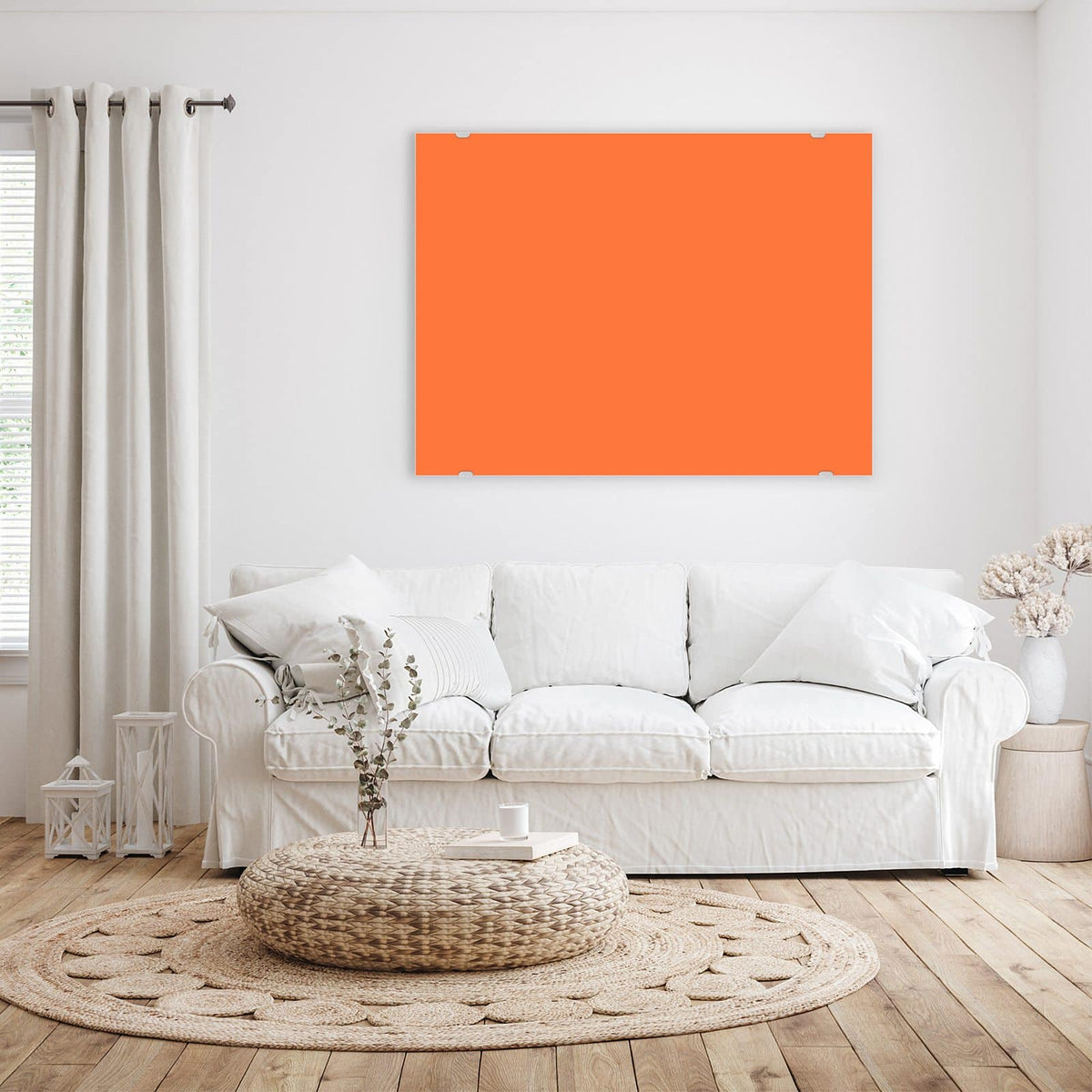 Wandbild aus Glas Korallenorange über einem weißen Sofa im hellen Wohnzimmer