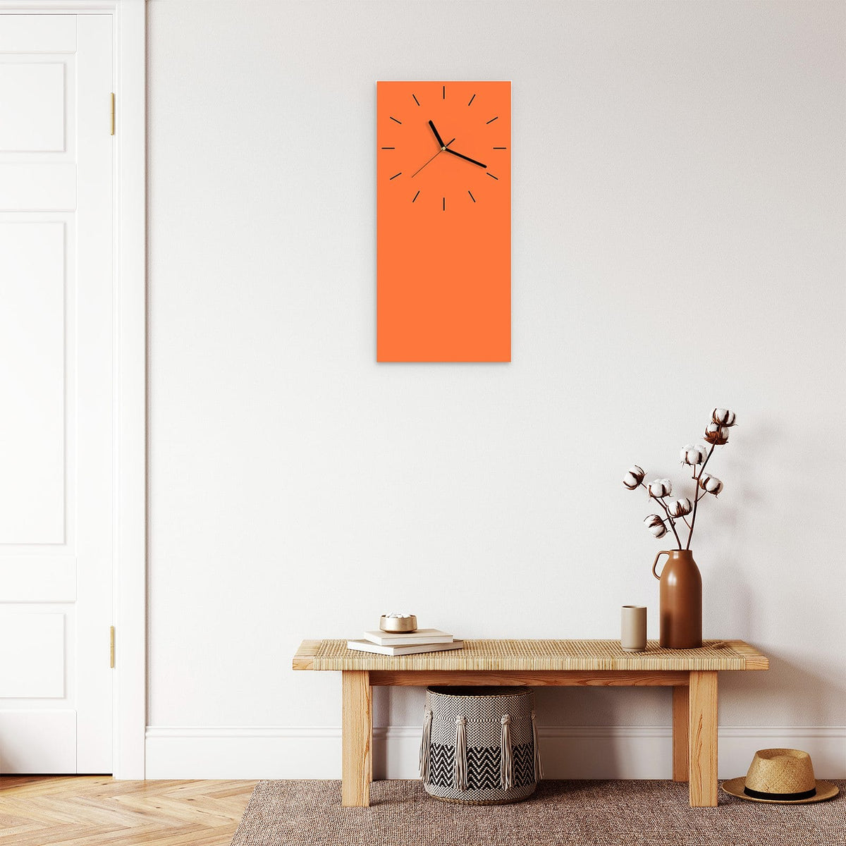 Wanduhr aus Glas im Hochformat Korallenorange mit Ziffernblatt Linie über einer Holzbank im Flur