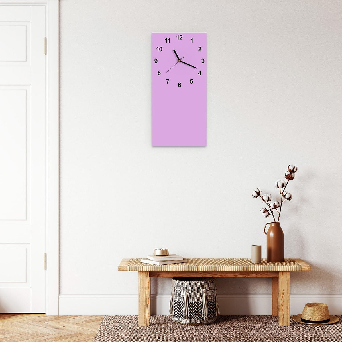 Wanduhr aus Glas im Hochformat Fliederlila mit Ziffernblatt Modern über einer Holzbank im Flur