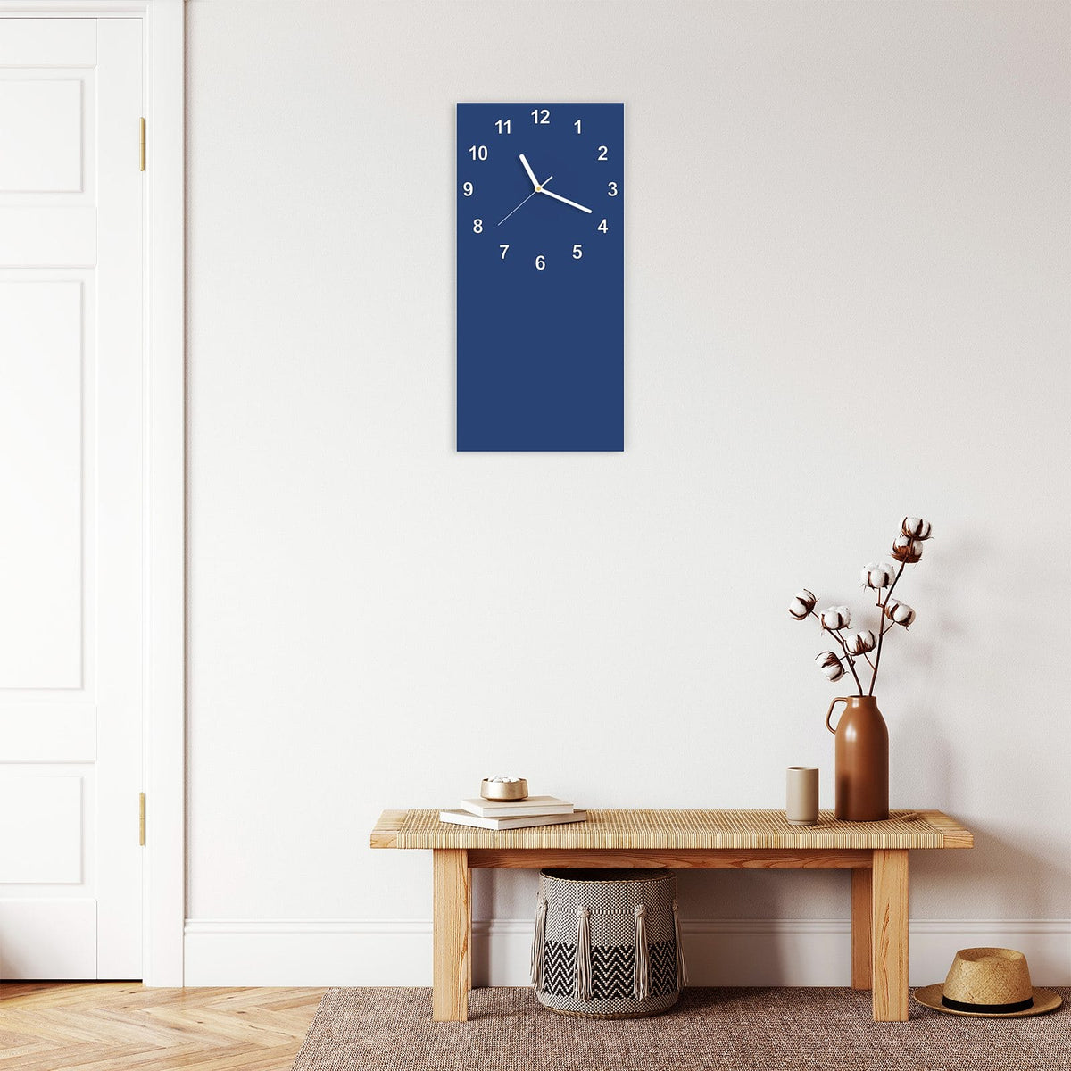 Wanduhr aus Glas im Hochformat Jeansblau mit Ziffernblatt Modern über einer Holzbank im Flur
