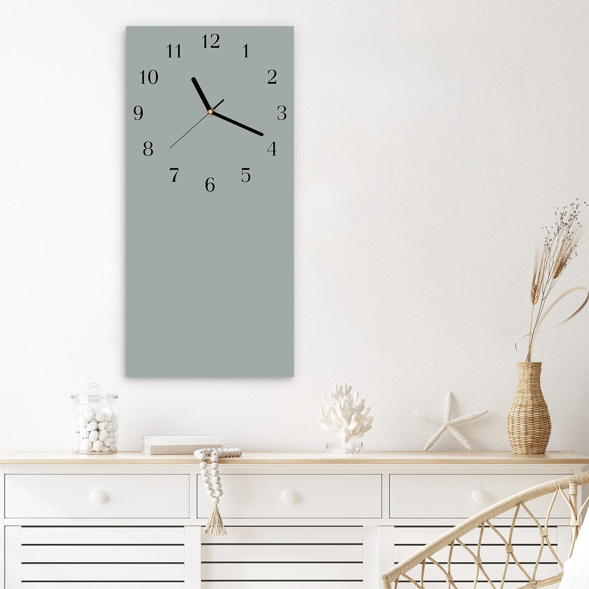 Wanduhr aus Glas im Hochformat Nebelgrau mit Ziffernblatt Klassisch über einem weißen Sideboard