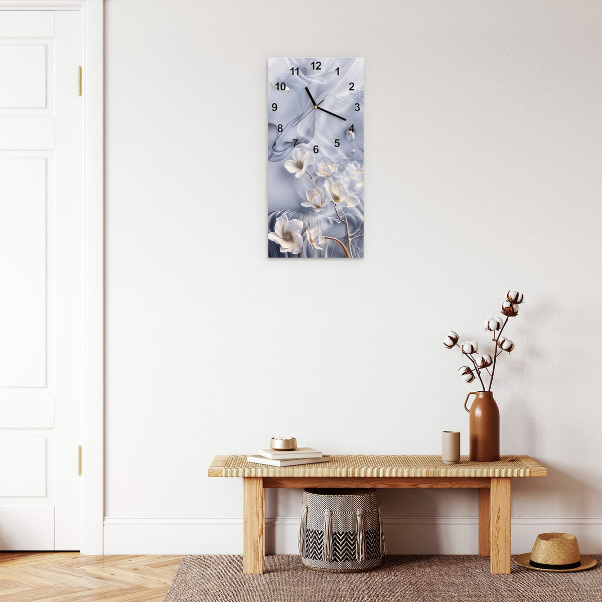 Wanduhr aus Glas im Hochformat Weiße Blüten auf Seide mit Ziffernblatt Modern über einer Holzbank im Flur