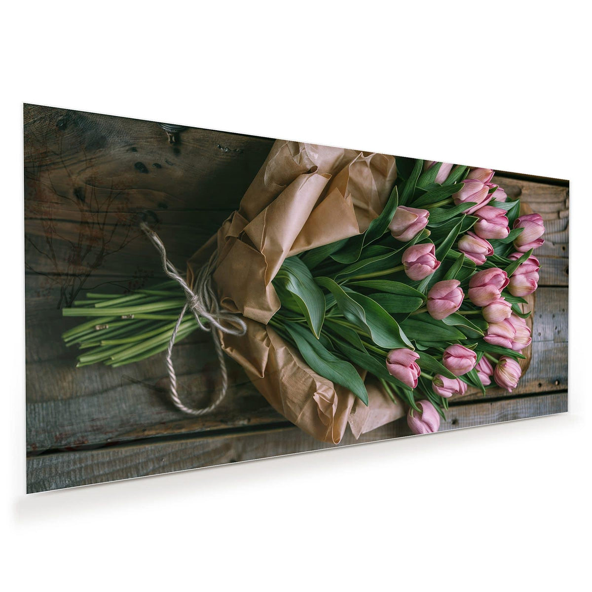Rosa Tulpen mit grünen Blättern in braunem Packpapier auf Holzdielen