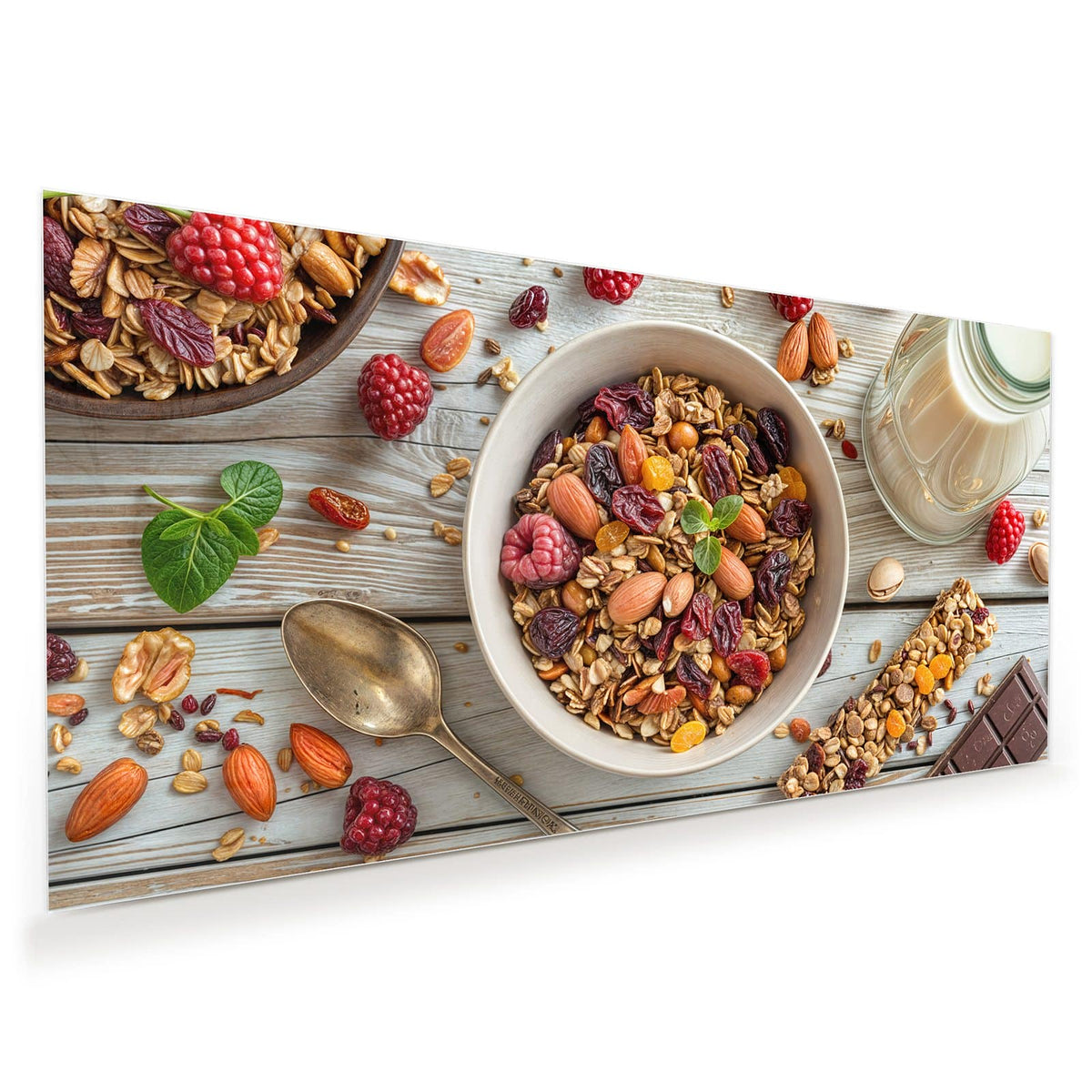 Schale mit Granola, Mandeln, Nüssen, Cranberrys und Rosinen auf hellem Holz, dazu Himbeeren, Löffel, Müsliriegel und ein Glas Tee.