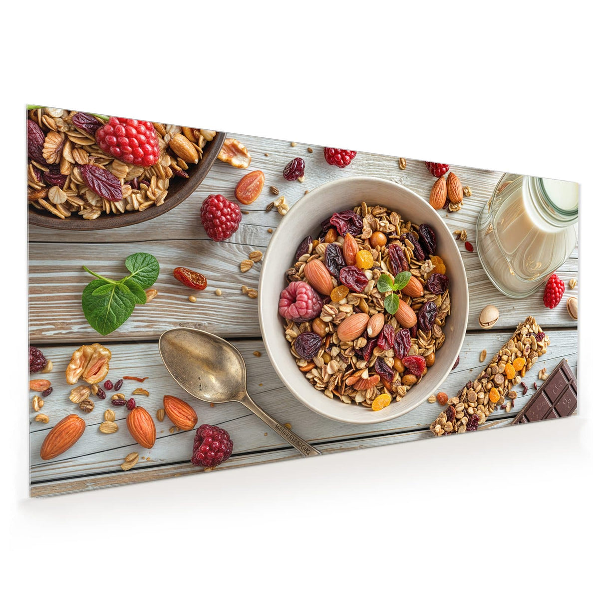 Schale mit Granola, Mandeln, Nüssen, Cranberrys und Rosinen auf hellem Holz, dazu Himbeeren, Löffel, Müsliriegel und ein Glas Tee.