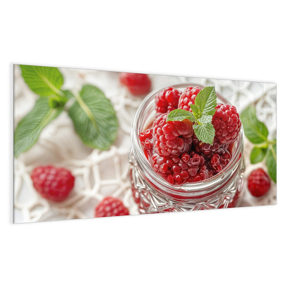 Einmachglas voller Himbeeren mit Minzblatt auf weißer Spitzendecke
