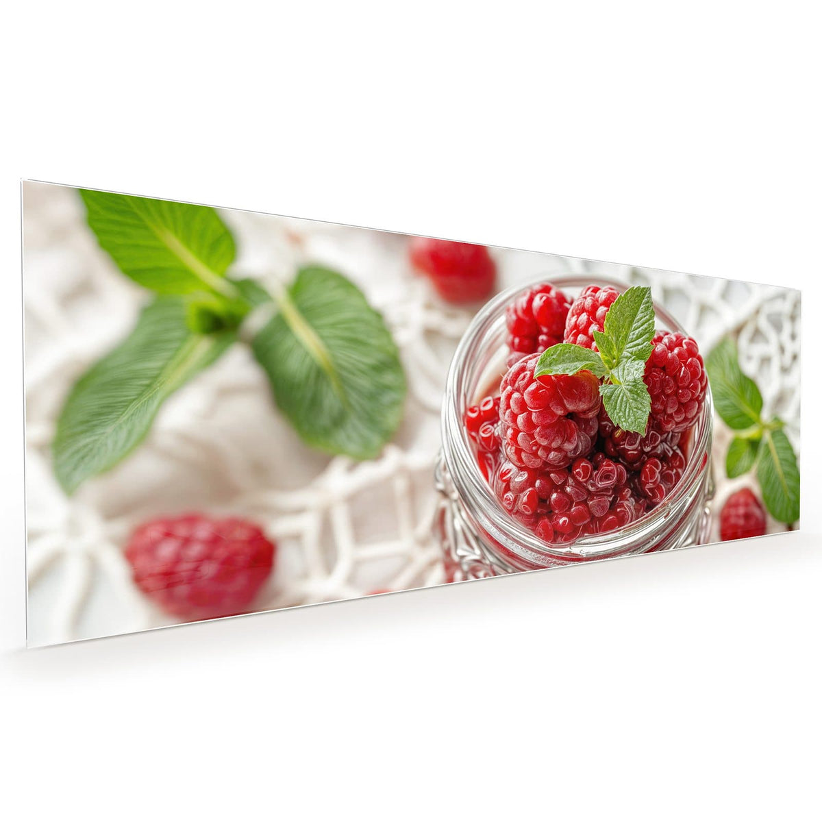 Küchenrückwand aus Glas im Hochformat mit Motiv Glas mit Himbeeren: Einmachglas voller Himbeeren mit Minzblatt auf weißer Spitzendecke