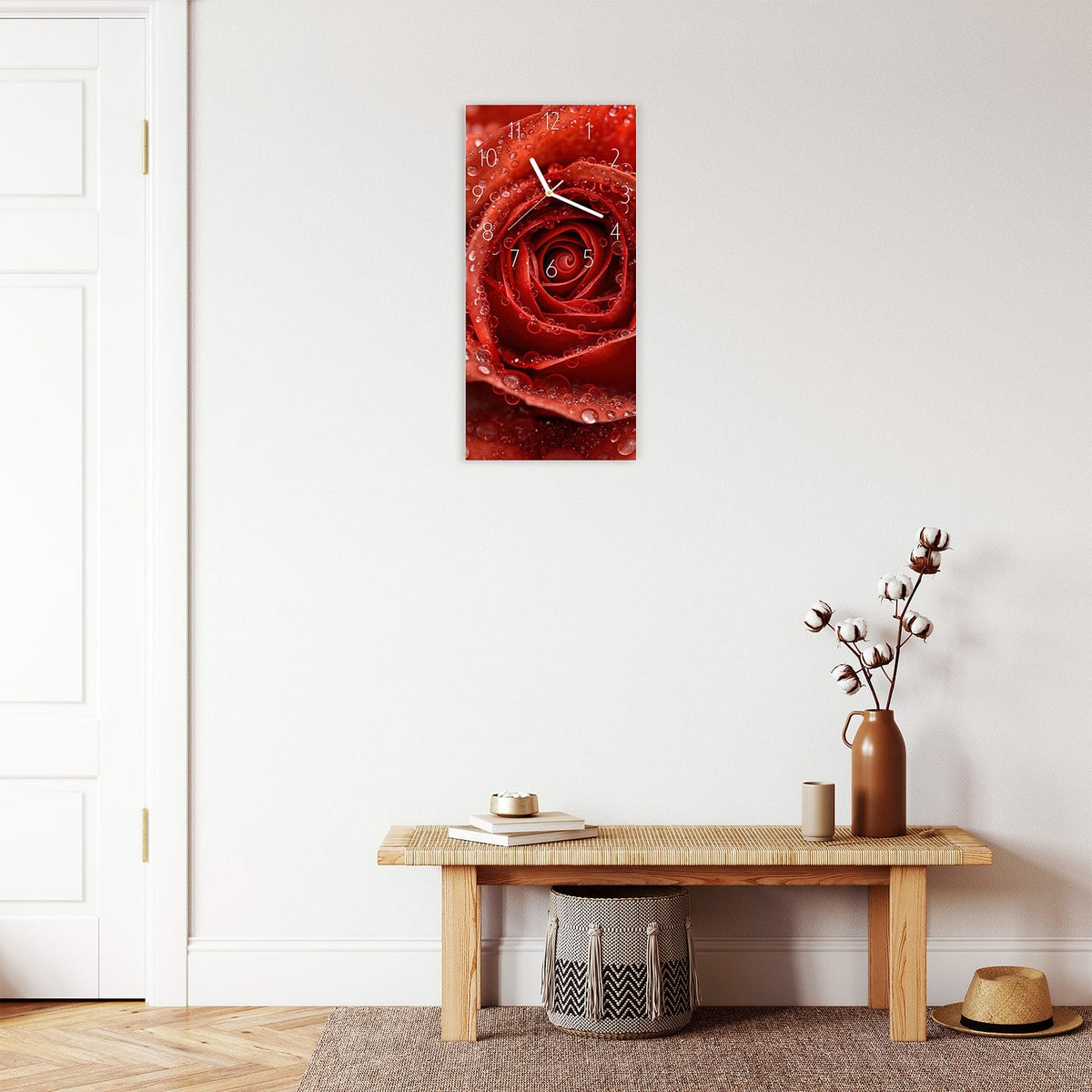 Wanduhr aus Glas im Hochformat Rote Rose mit Tropfen mit Ziffernblatt Elegant über einer Holzbank im Flur