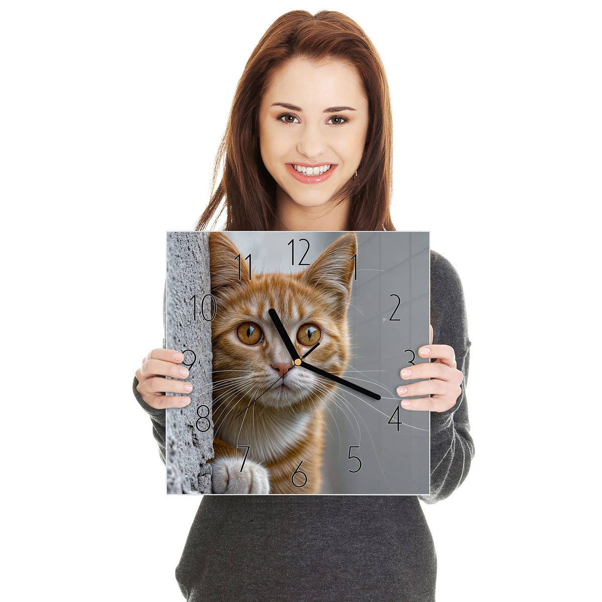 Orange getigerte Katze lugt hinter einer grauen Betonmauer hervor, eine Pfote am Rand