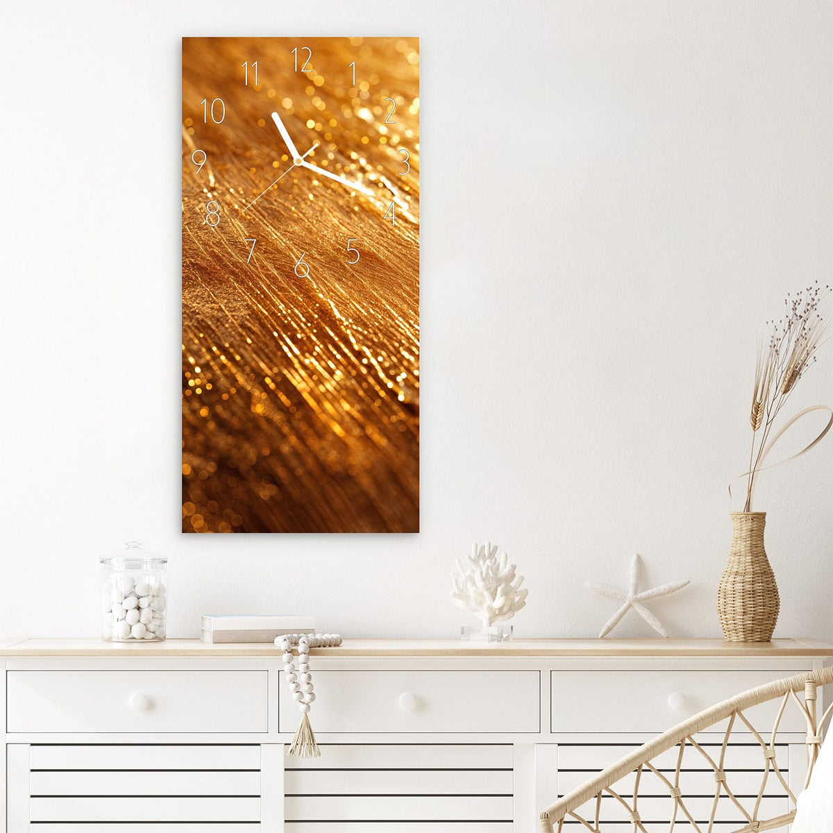 Wanduhr aus Glas im Hochformat Schimmerndes Gold mit Ziffernblatt Elegant über einem weißen Sideboard