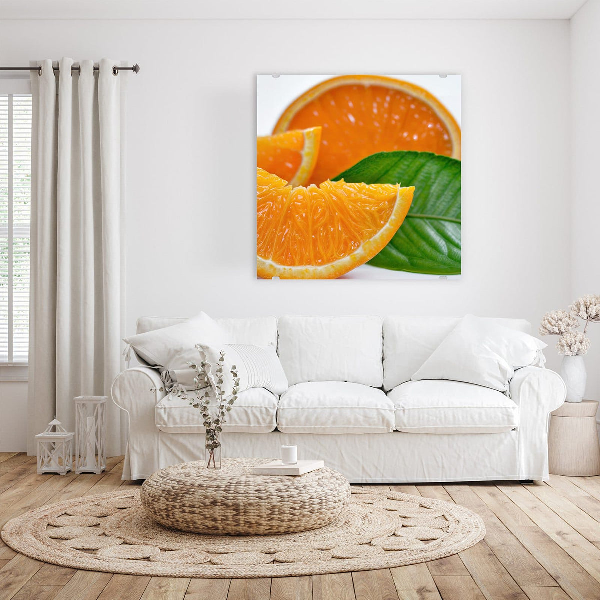 Glasbild Orangenscheiben an der Wand – Saftige Orangenspalten und eine halbe Orange mit großem grünem Blatt vor Weiß