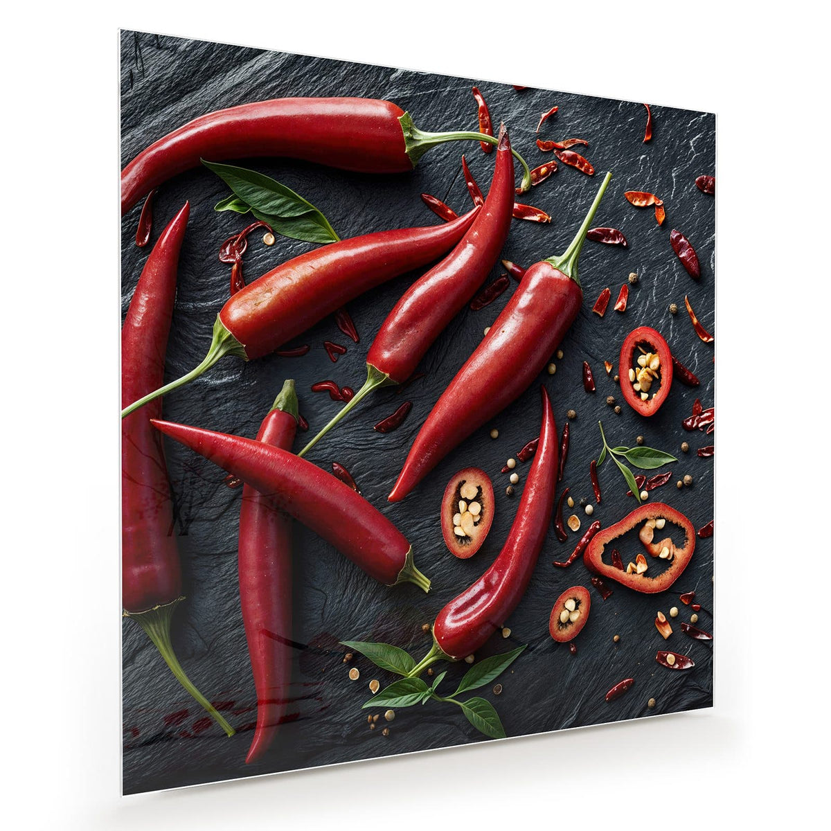 Acht leuchtend rote Chilischoten, einige Ringe und getrocknete Flocken auf dunklem Schiefer