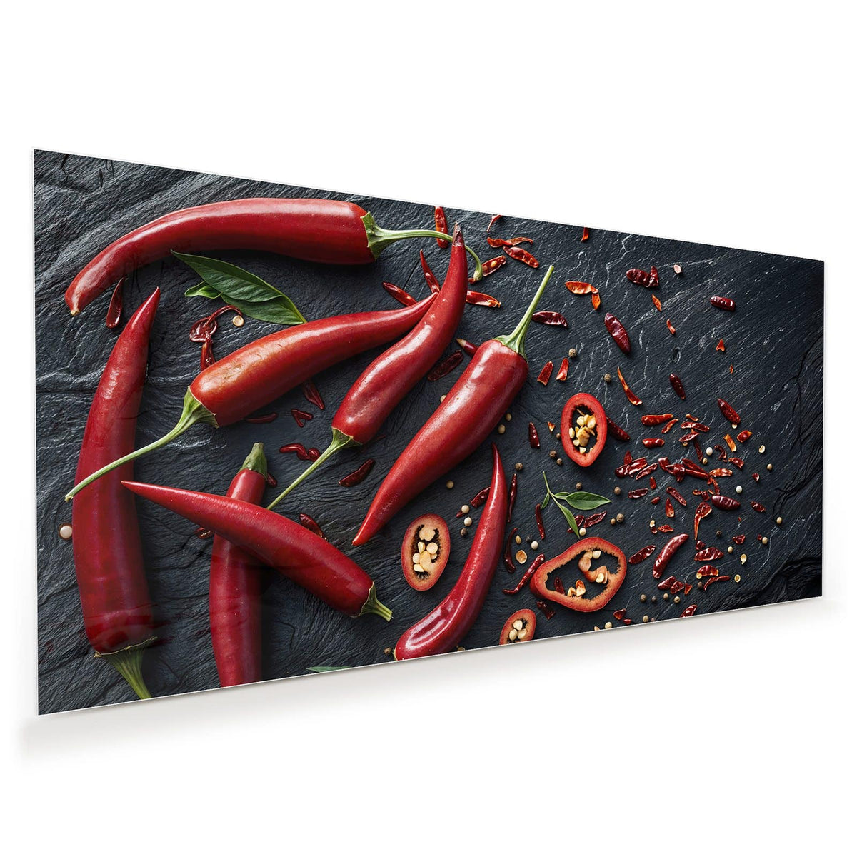 Acht leuchtend rote Chilischoten, einige Ringe und getrocknete Flocken auf dunklem Schiefer