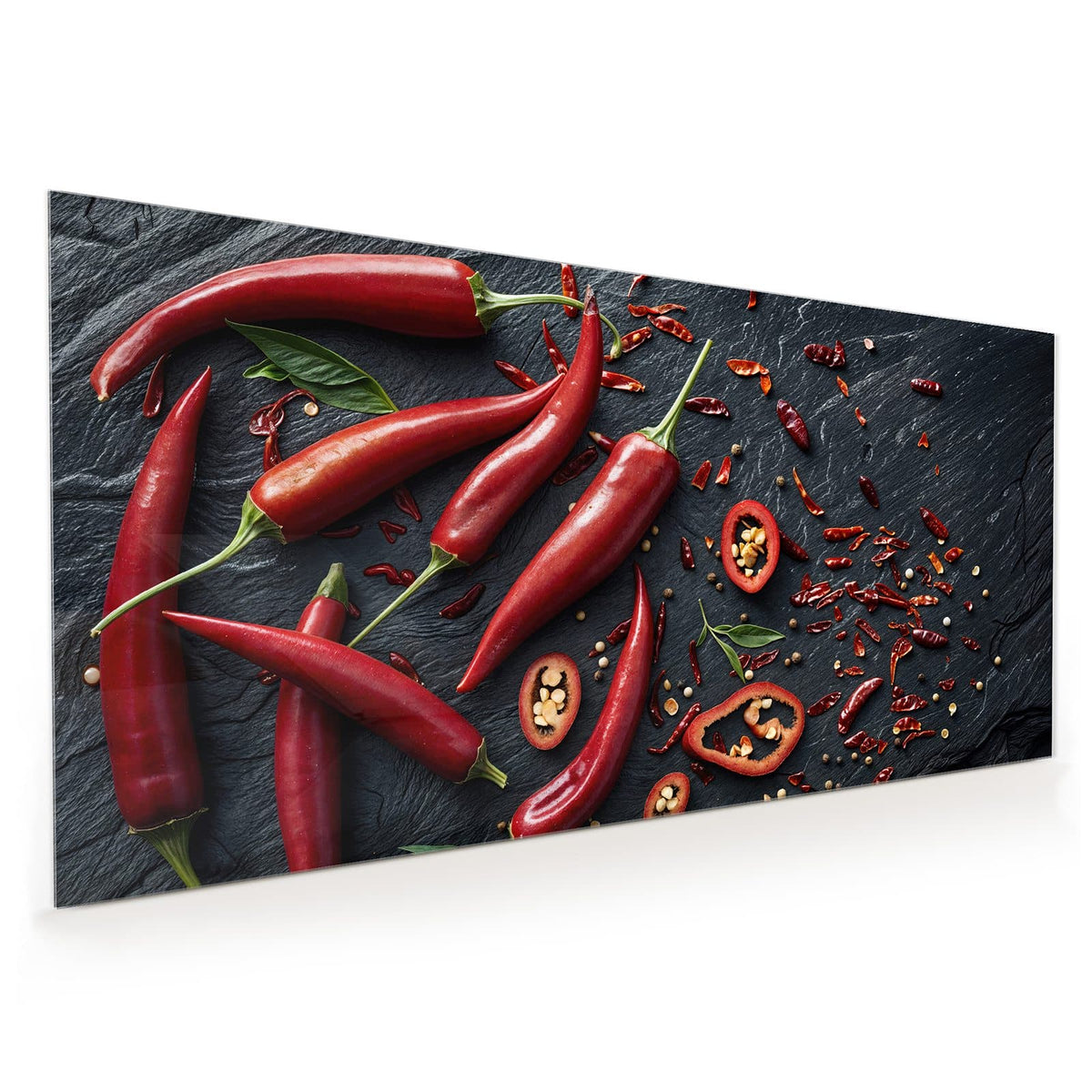 Acht leuchtend rote Chilischoten, einige Ringe und getrocknete Flocken auf dunklem Schiefer