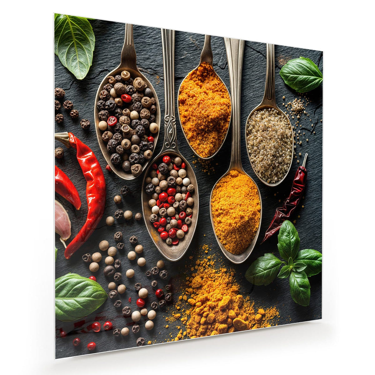 Antike Silberlöffel mit Pfeffermix, Kurkuma und grobem Salz auf Schiefer, dazu Chilis und Basilikum