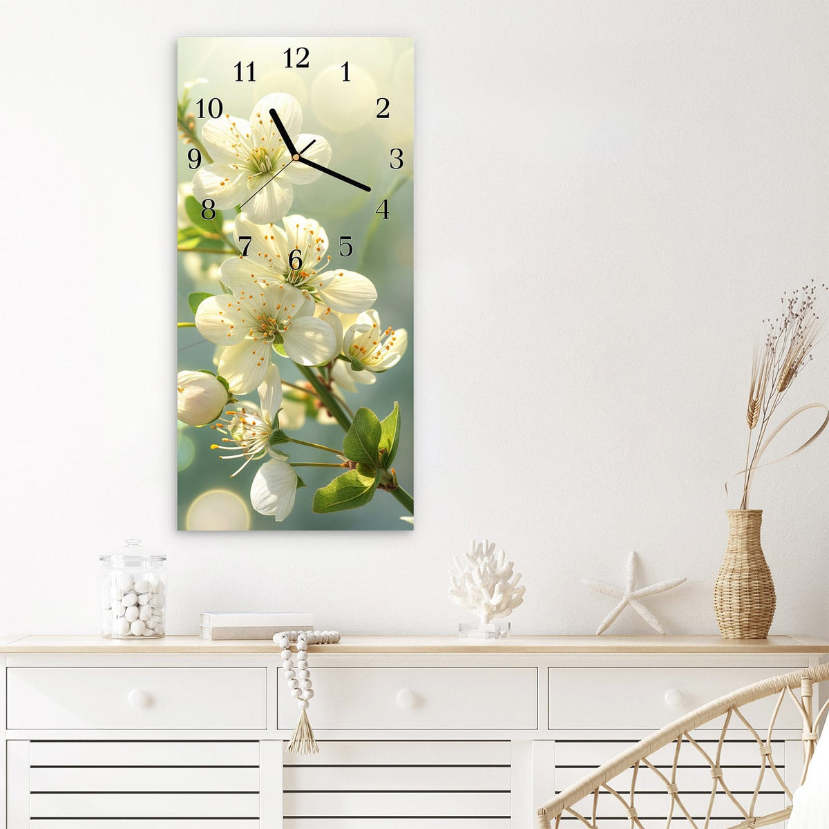 Wanduhr aus Glas im Hochformat Weiße Blüten vor Grün mit Ziffernblatt Klassisch über einem weißen Sideboard