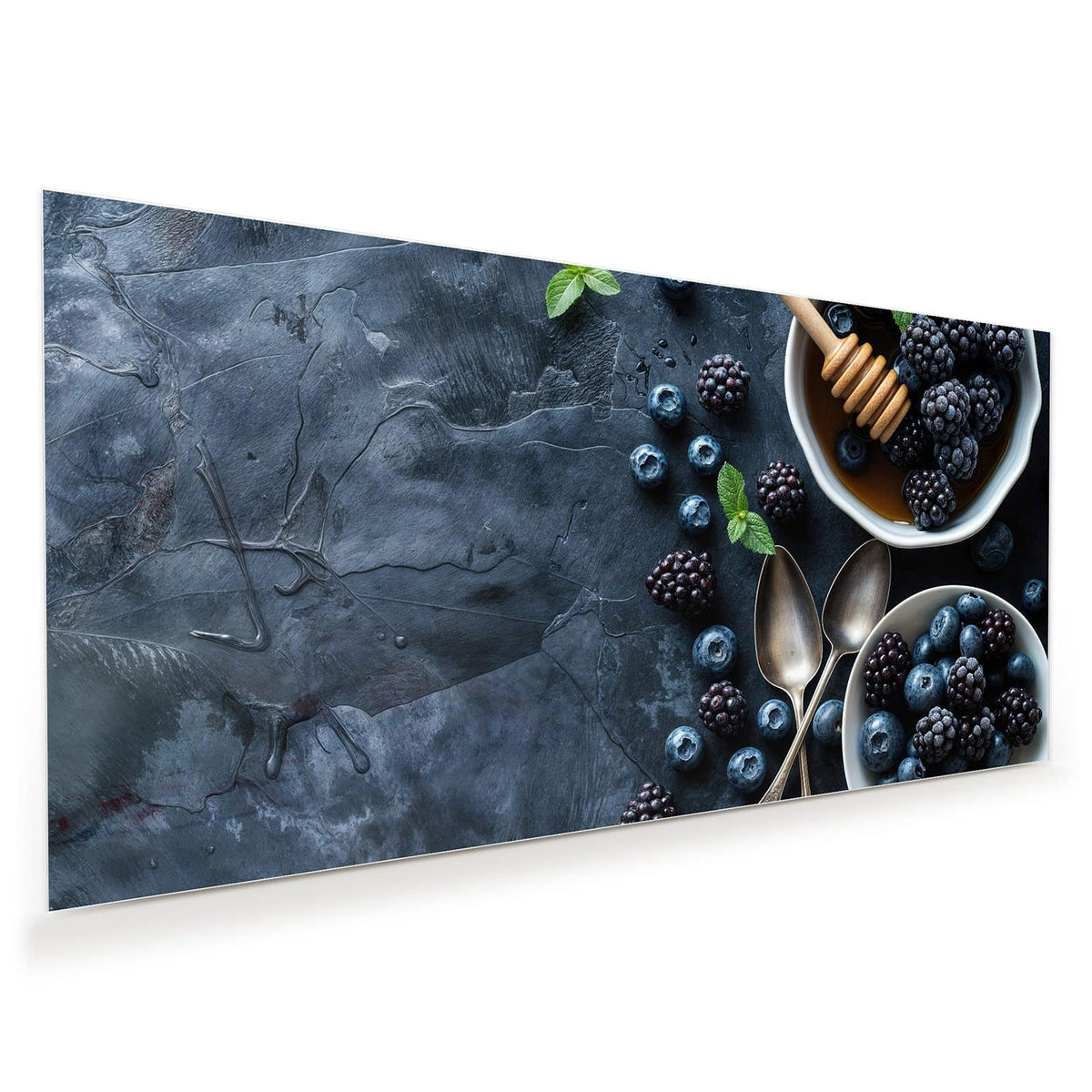Zwei weiße Schalen mit Heidel- und Brombeeren, Honig mit Honiglöffel, Minze und alte Löffel auf dunklem Schiefer.