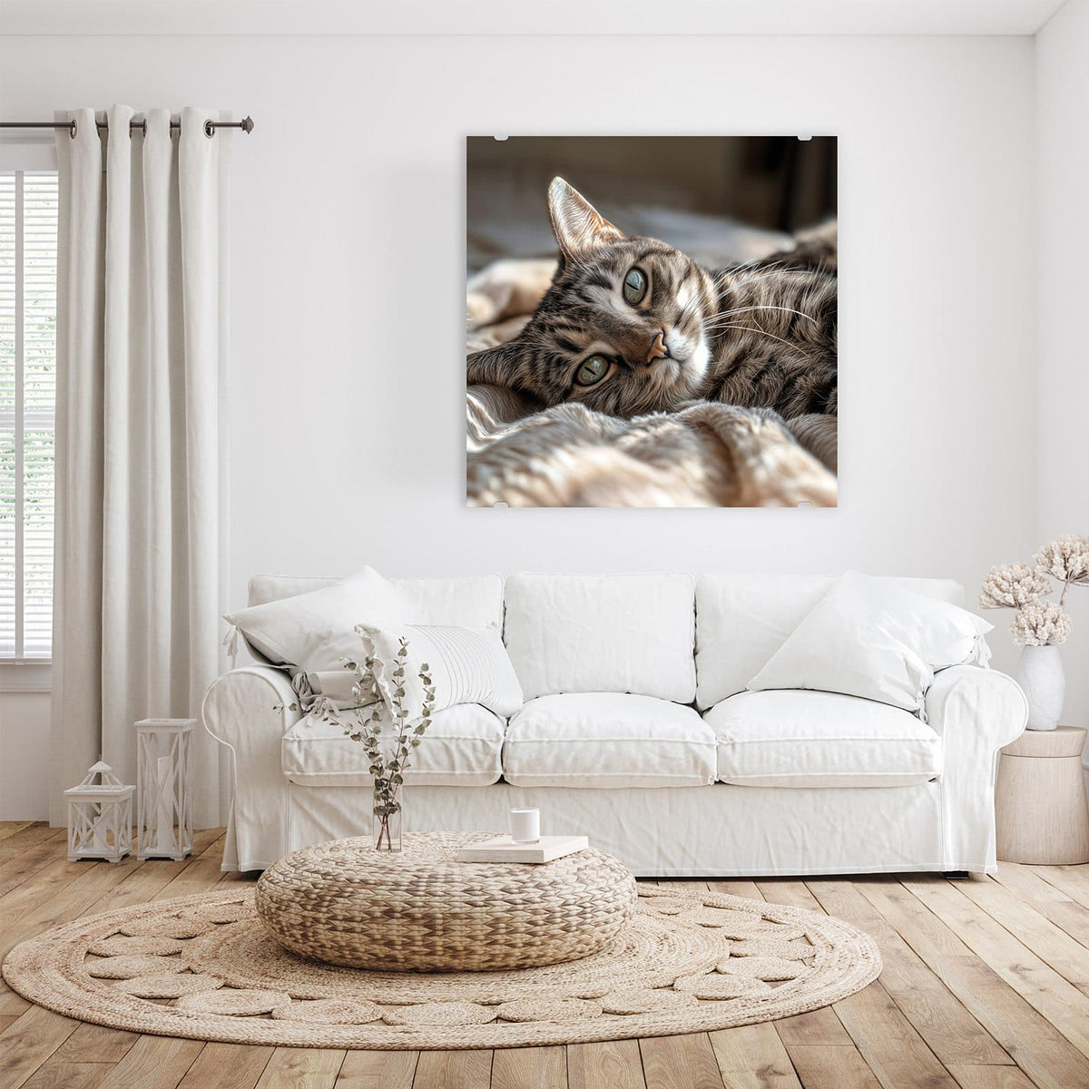 Glasbild Gemütliche Katze an der Wand – Getigerte Katze liegt entspannt auf einer hellen Decke und blickt zur Seite
