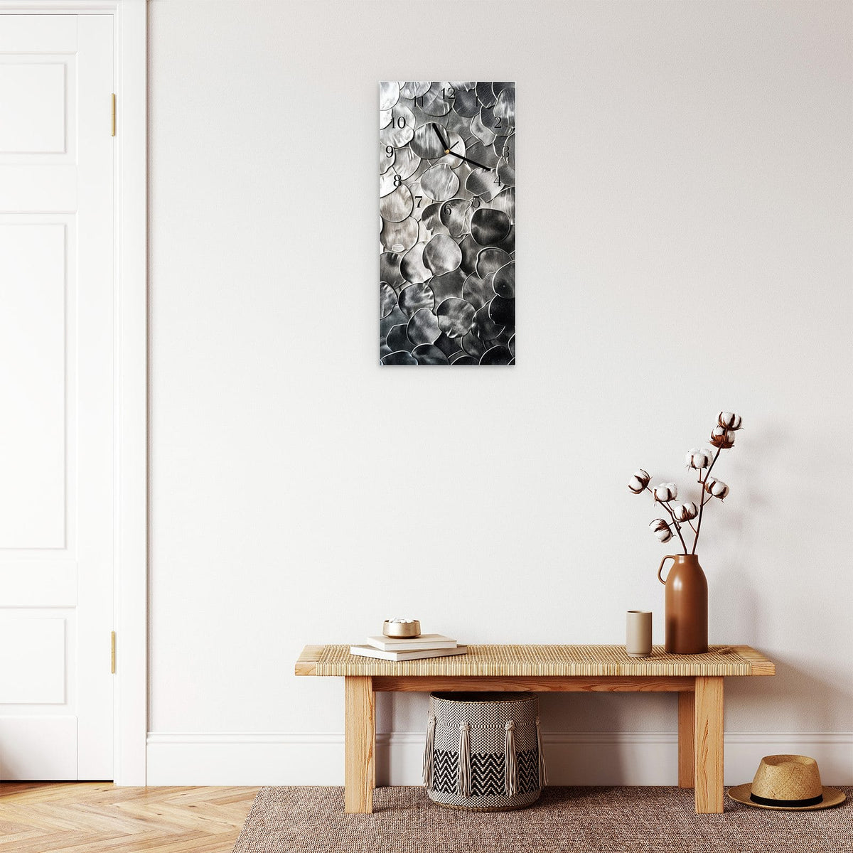 Wanduhr aus Glas im Hochformat Silberne Schuppen mit Ziffernblatt Klassisch über einer Holzbank im Flur