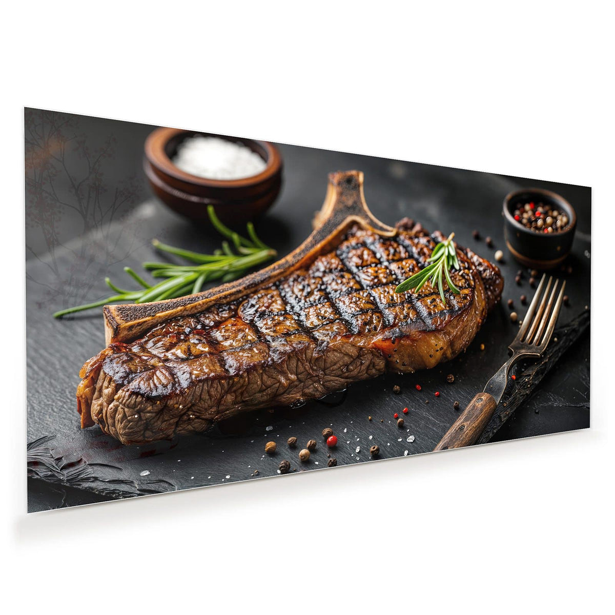 Angeschnittenes T-Bone-Steak mit Grillstreifen auf Schiefer, dazu Rosmarin, Salzschale und Pfefferkörner